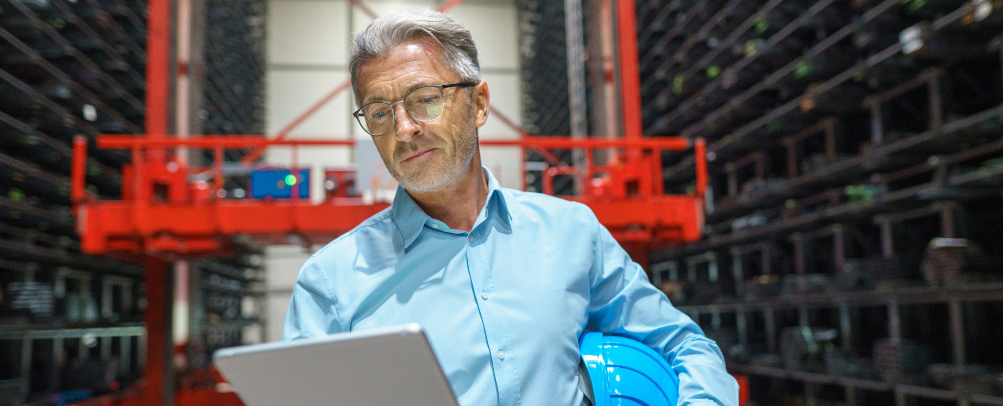 profissional em ambiente industrial consulta tablet e agarra em capacete