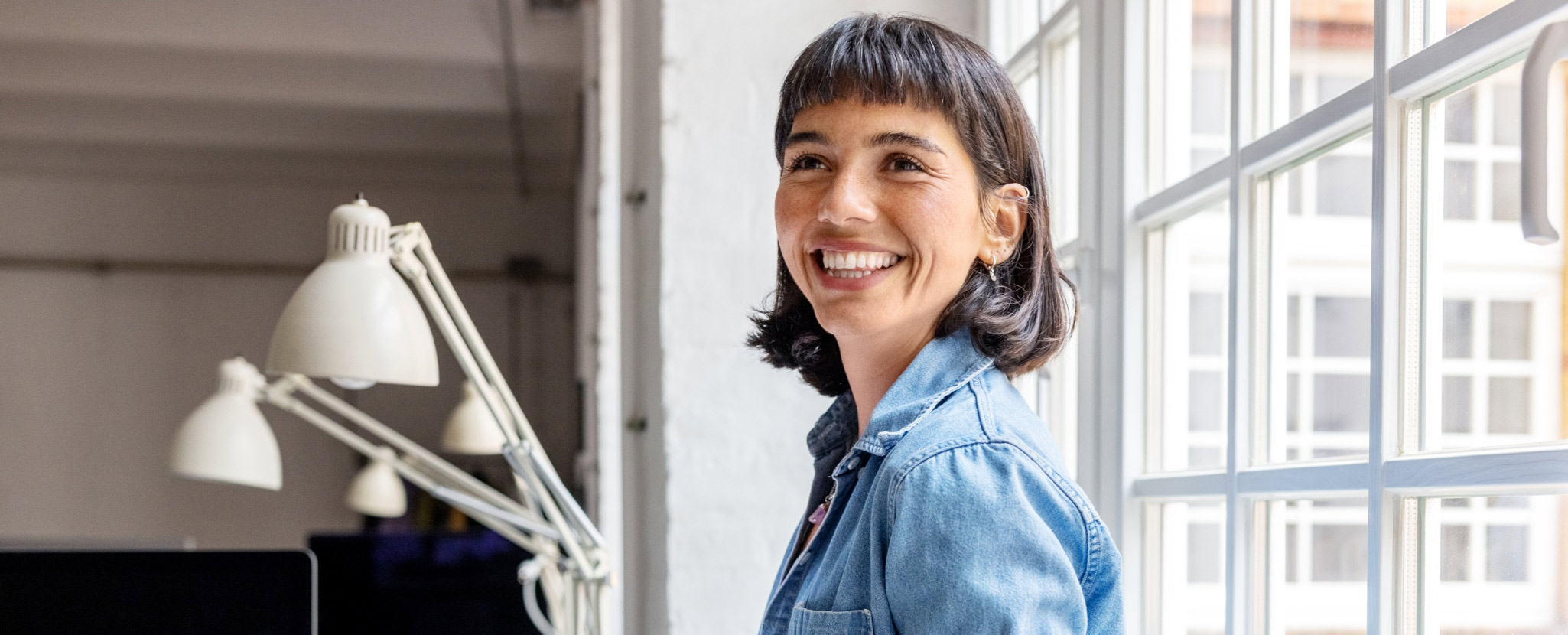 jovem mulher sorridente junto a janela