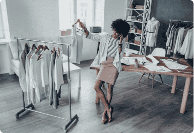 senhora ao telefone com um cabide com uma peça de roupa na mão