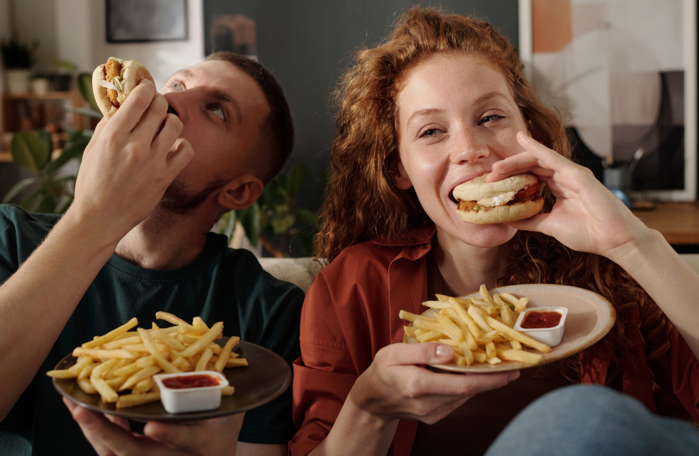 Casal jovem come fast-food no sofá de casa