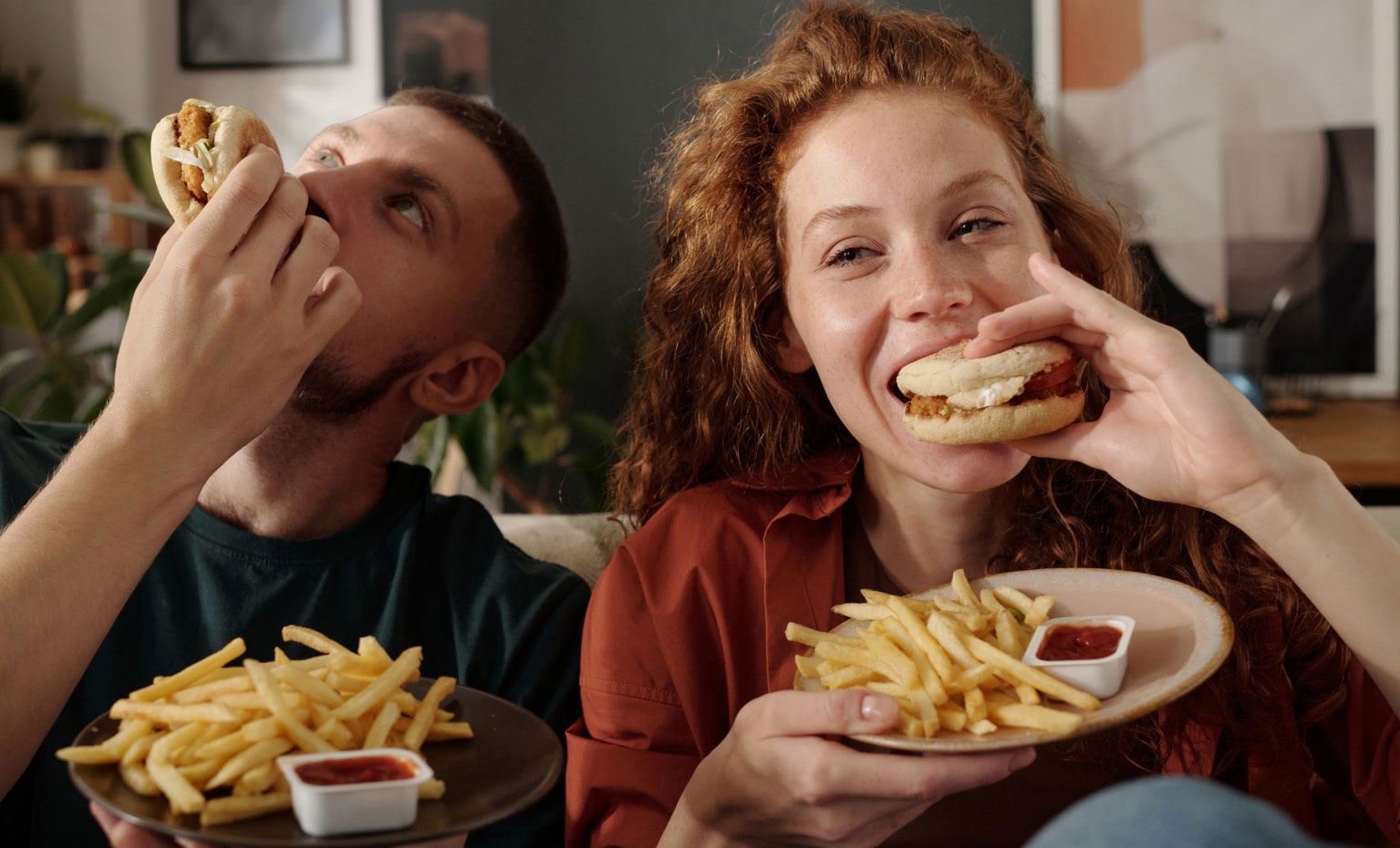 Casal jovem come fast-food no sofá de casa