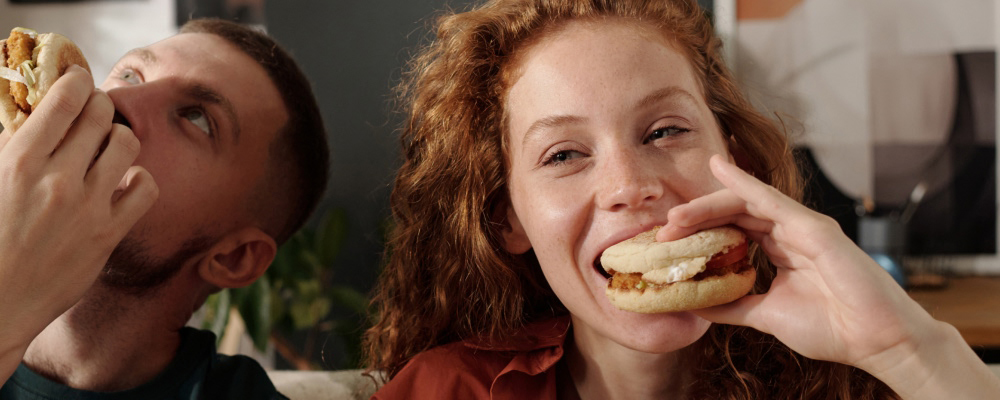 Casal jovem come fast-food no sofá de casa