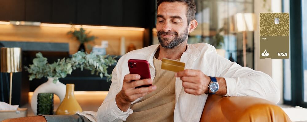 Homem sentado no sofá com o seu novo cartão de crédito