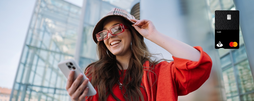 Mulher sorridente com o seu cartão de crédito Santander