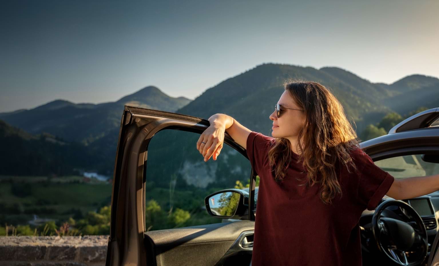 Mulher sai do carro e contempla paisagem