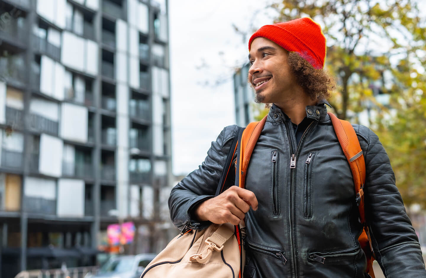Homem com mochila às costas sorri enquanto olha para o lado