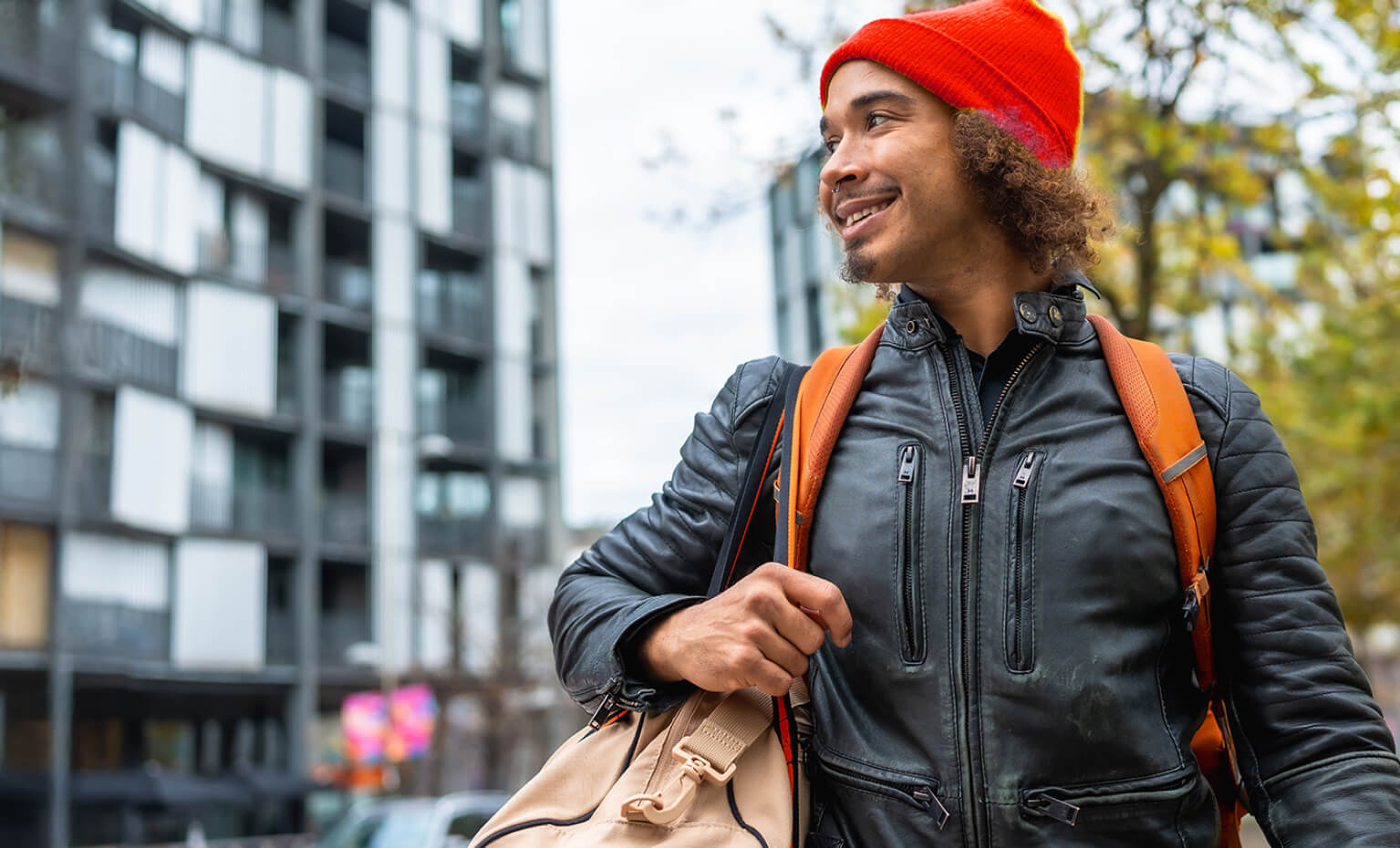 Homem com mochila às costas sorri enquanto olha para o lado
