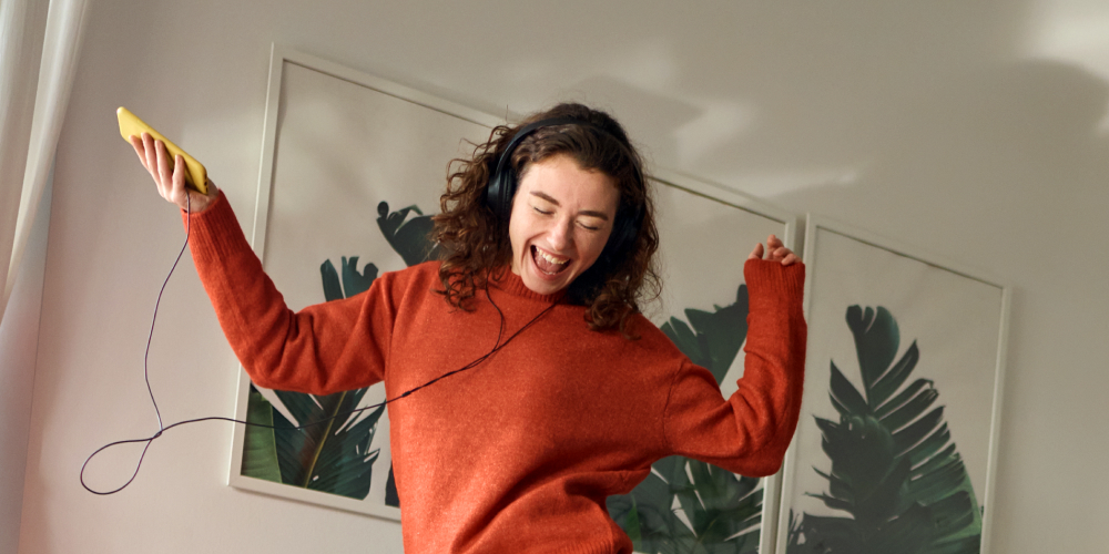 Menina dança animada com headphones nos ouvidos