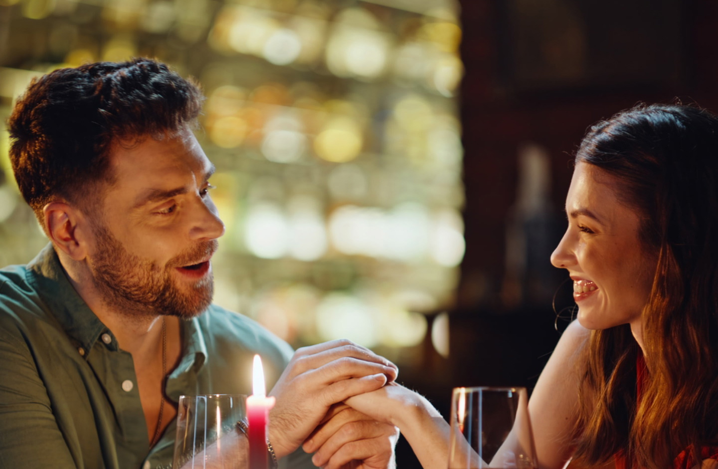 Casal de homem e mulher de mãos dadas partilha momento feliz à luz das velas