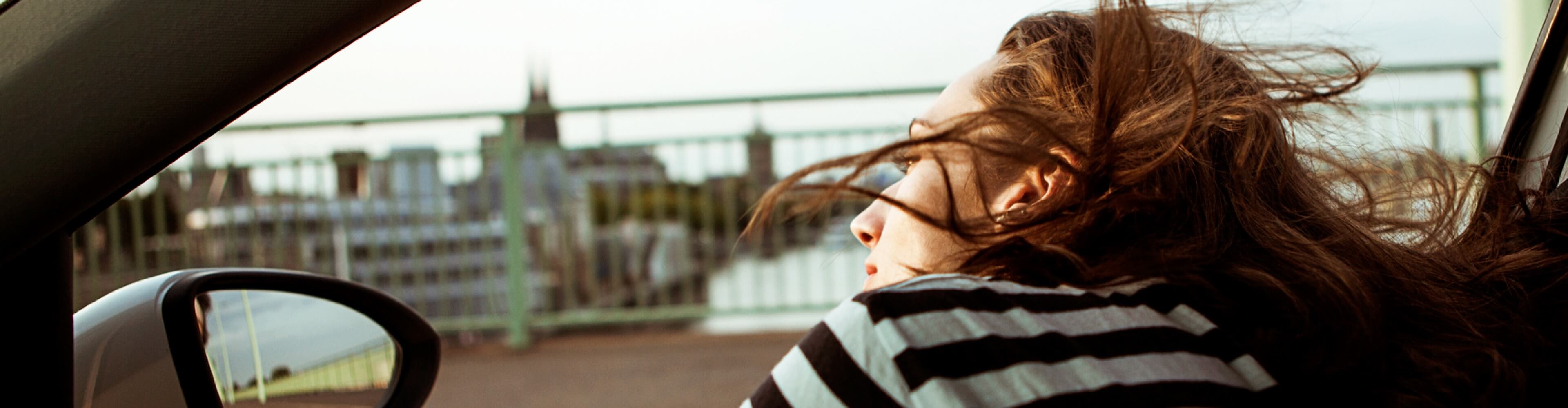 Mulher observa paisagem dentro de um automóvel