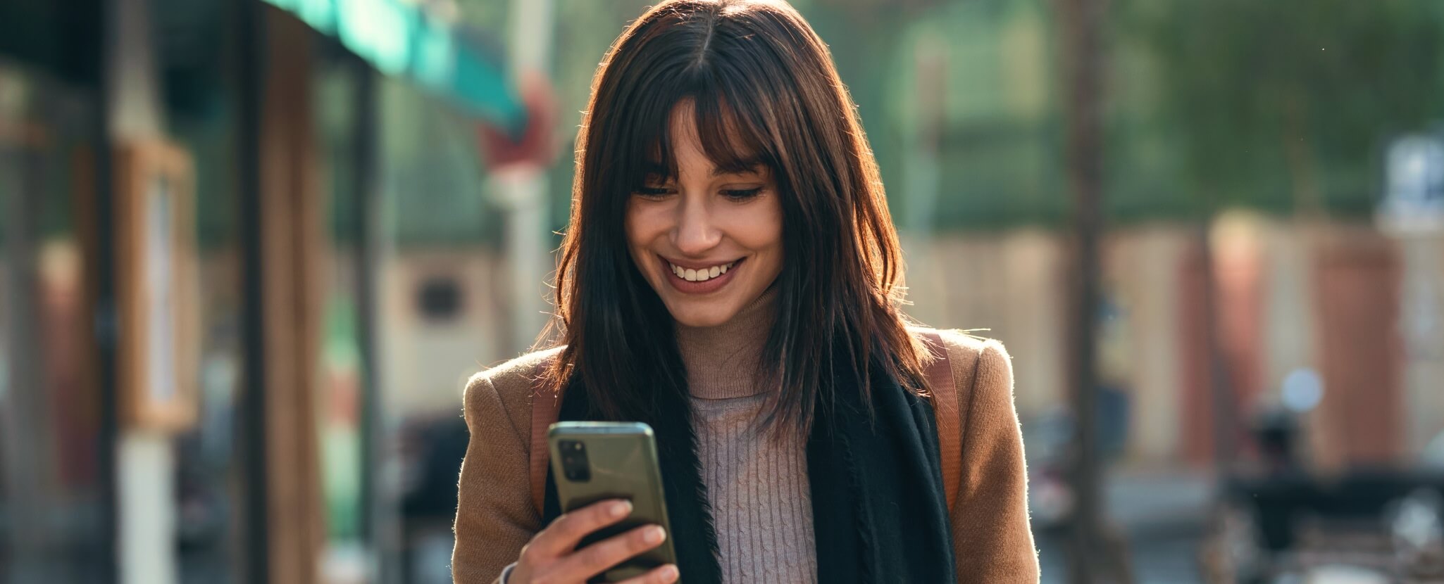 Mulher contempla com ar feliz o seu smartphone