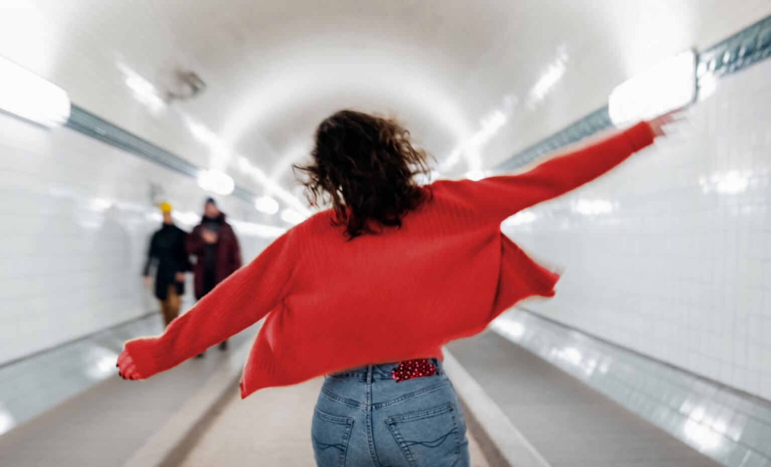 Mulher de braços abertos numa estação de metro