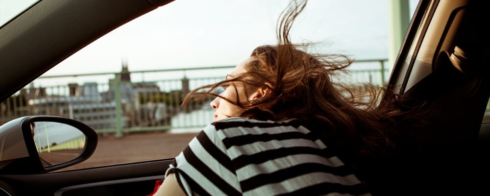 Mulher observa paisagem dentro de um automóvel