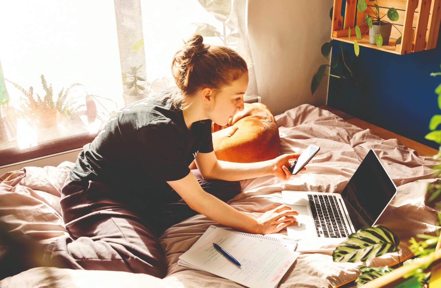 Mulher verifica informações no smartphone e no computador portátil no seu quarto