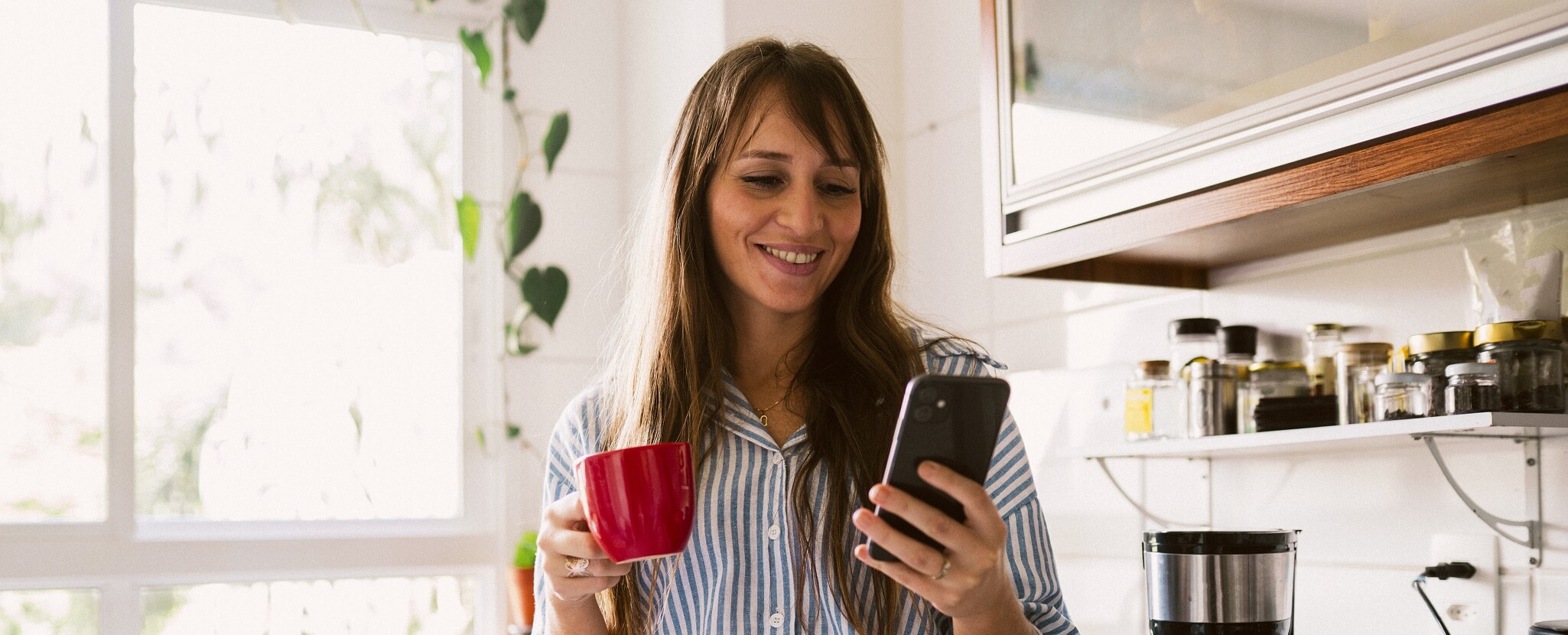 mulher ao telemóvel a segurar caneca