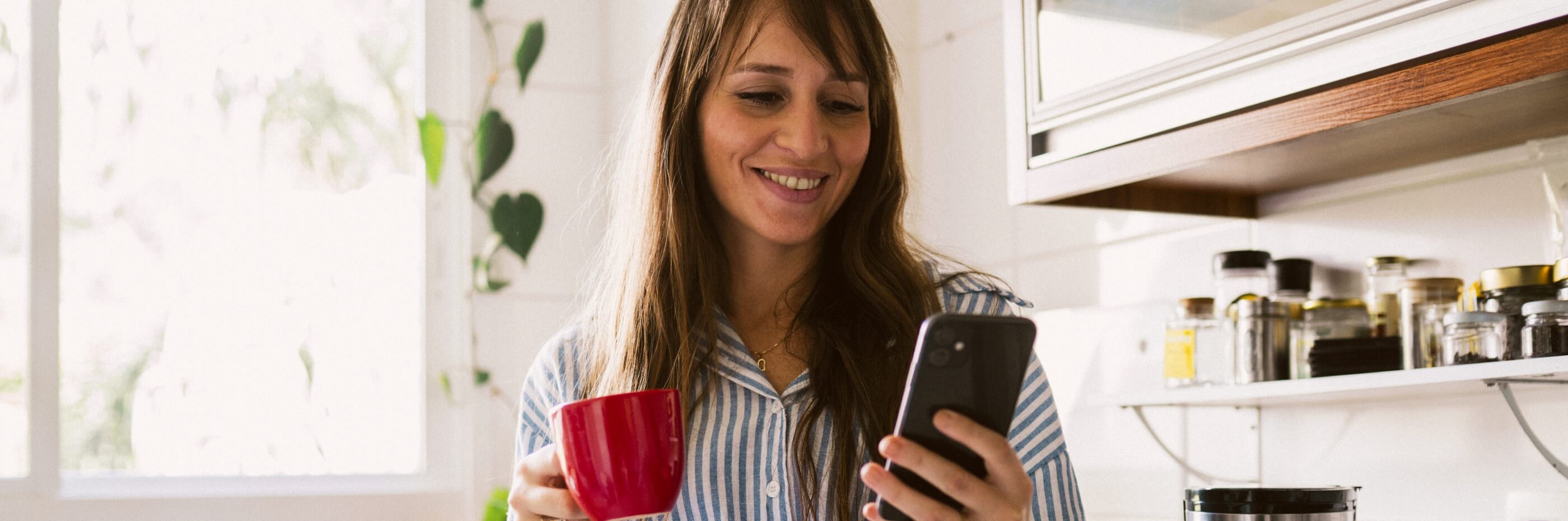 mulher ao telemóvel a segurar caneca