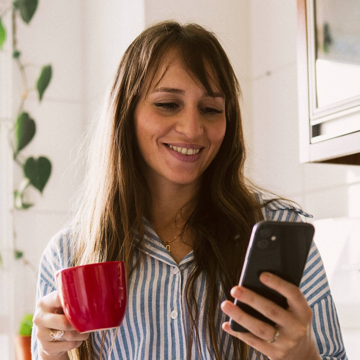 mulher ao telemóvel a segurar caneca