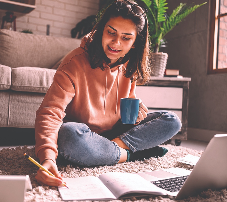jovem com laptop e a anotar em caderno