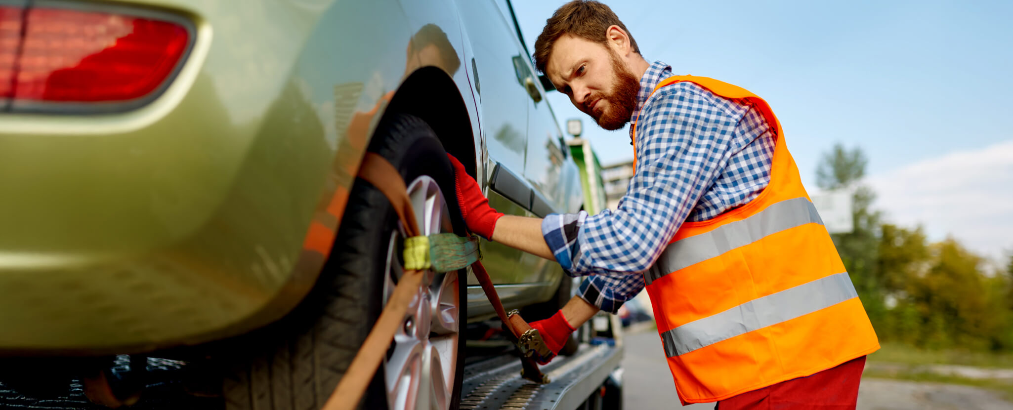 Homem com colete refletor substitui pneu de automóvel