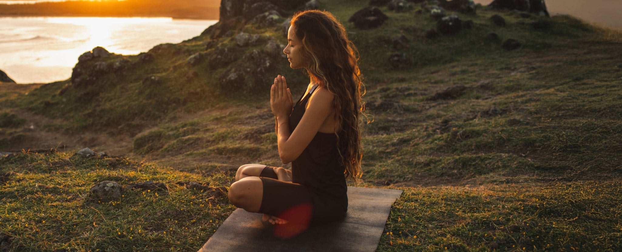 mulher medita em tapete de ioga ao ar livre