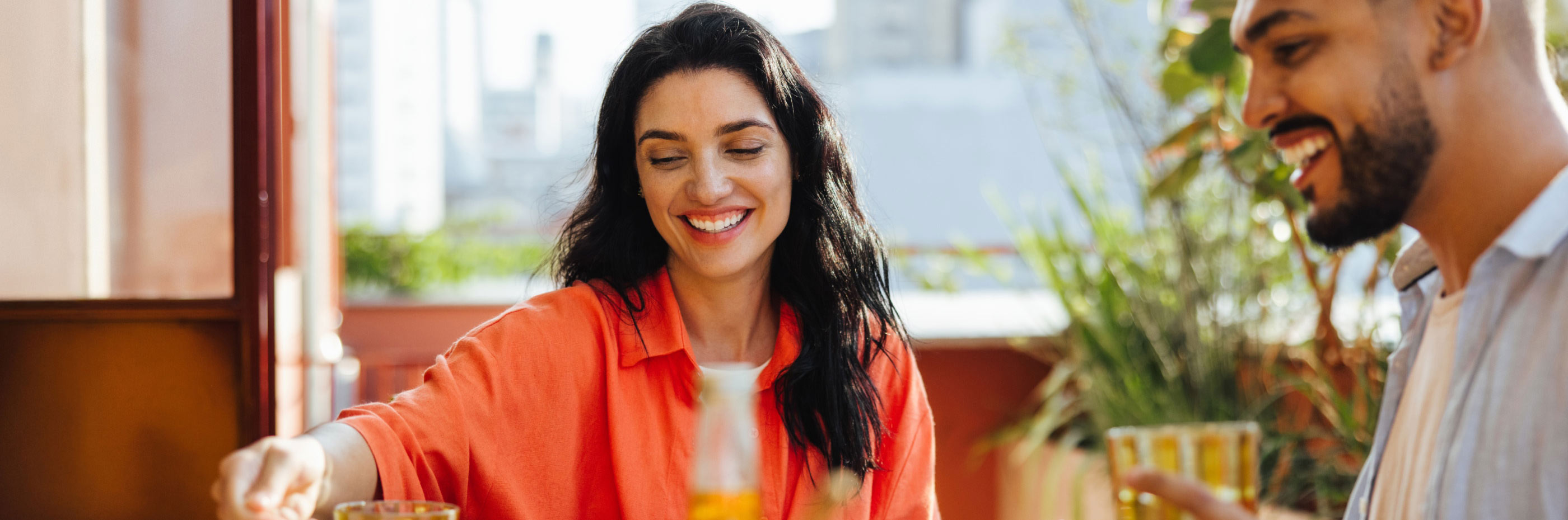 mulher sorridente serve bebida a homem em contexto caseiro
