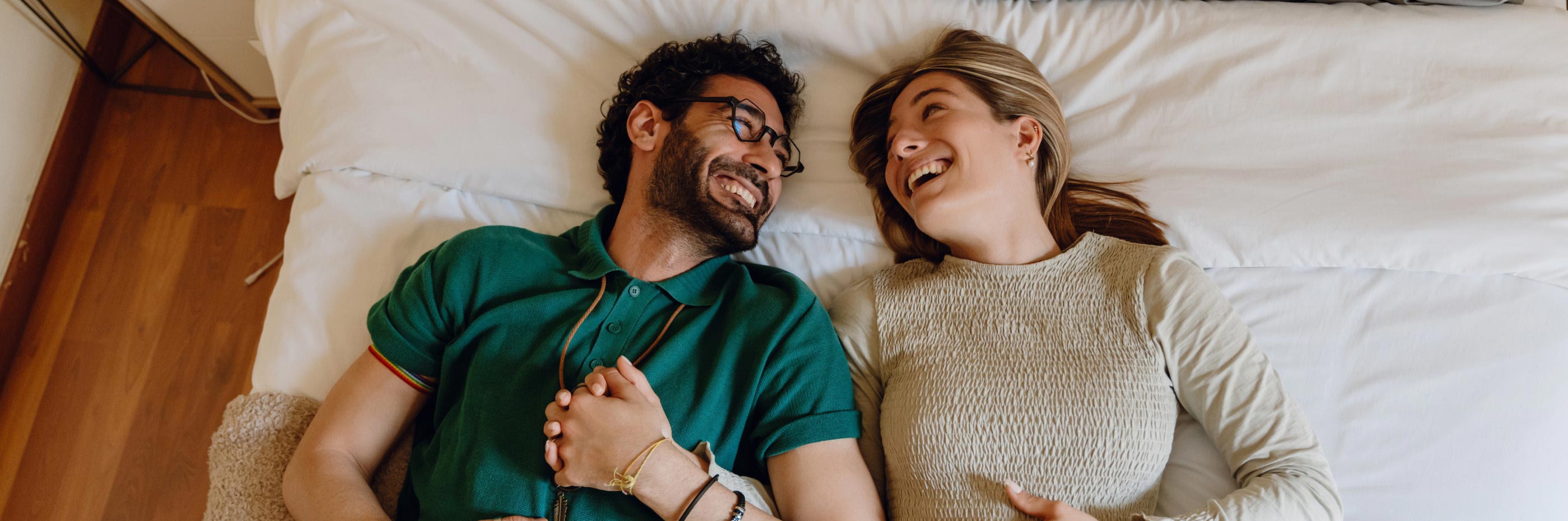 Casal de homem e mulher abraçados em cima da cama da sua casa nova
