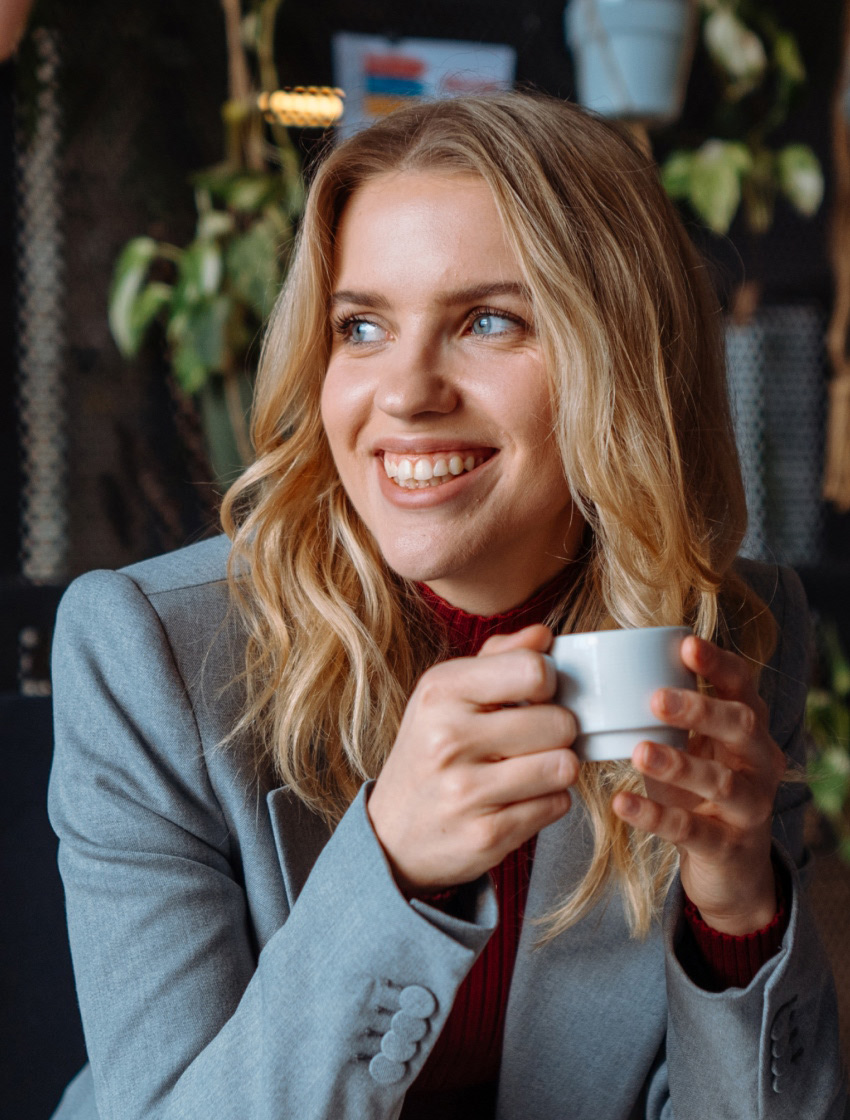 Mulher sorri enquanto toma café