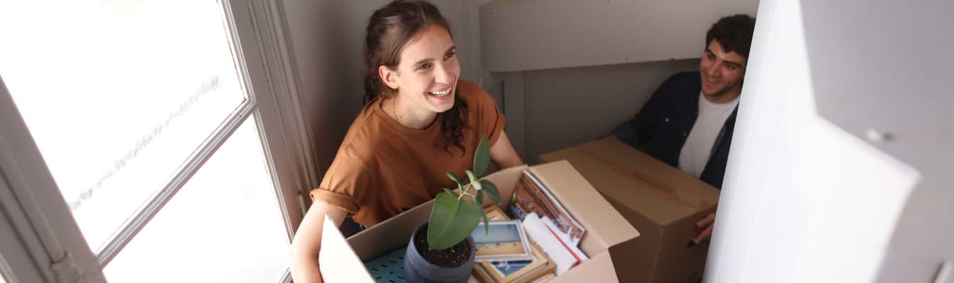 Mulher transporta caixa de mudanças escada acima