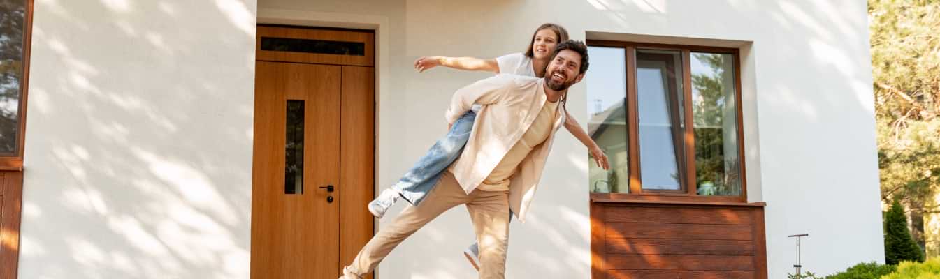 Casal feliz em frente à sua habitação