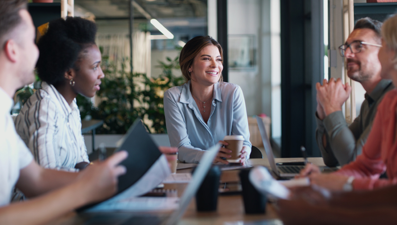Quatro pessoas numa reunião, sentadas à volta de uma mesa e a conversar sobre um projeto