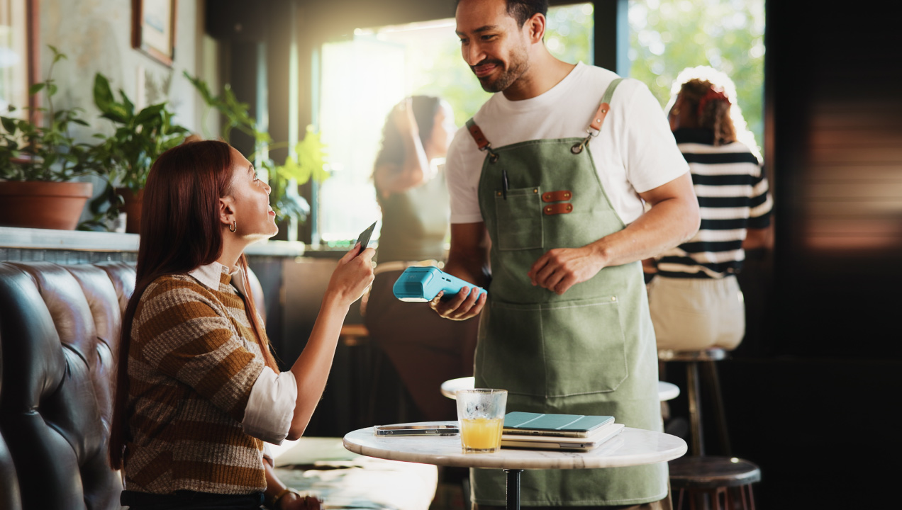 Cliente num restaurante a usar o telemóvel para efetuar um pagamento