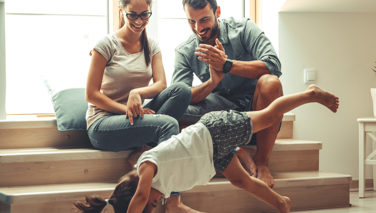 Casal sentado e feliz a ver a filha a fazer a roda