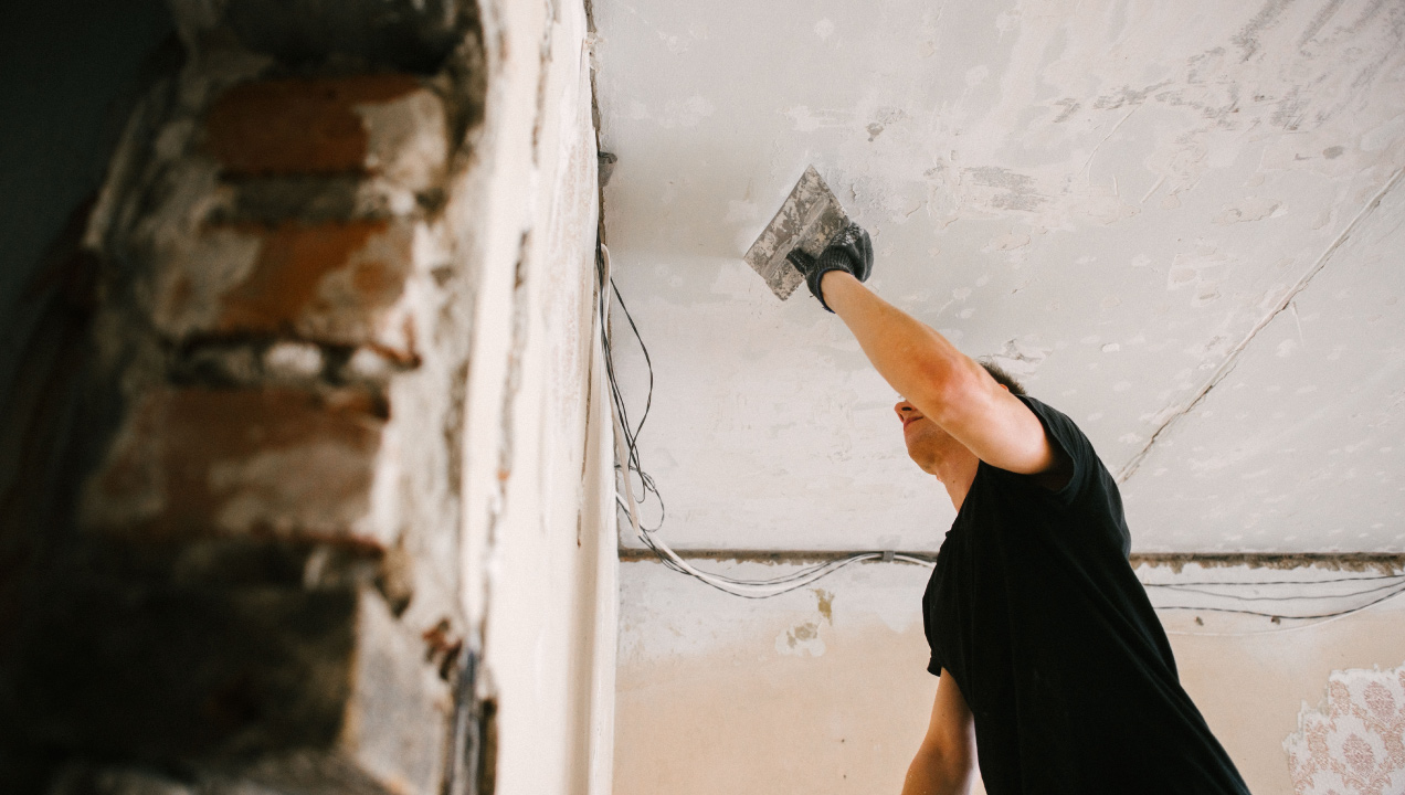 Senhor a aplicar revestimento no teto durante obras de renovação de uma casa antiga