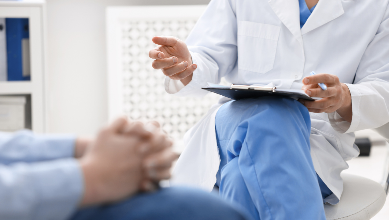 Senhor sentado num consultório medico a conversar com um médico 