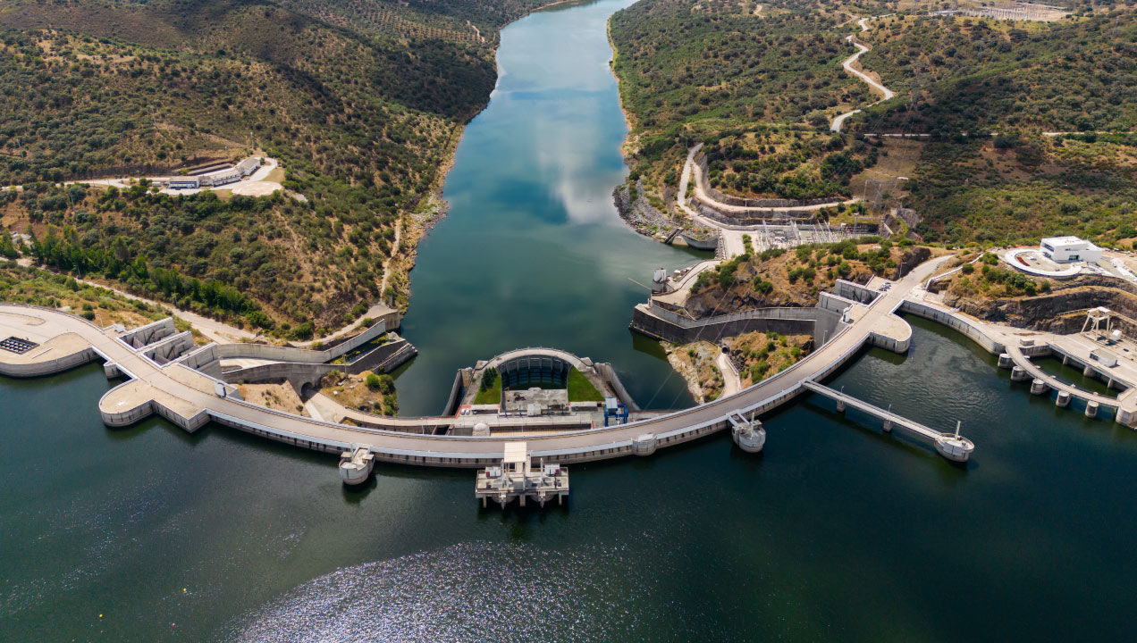 Vista aérea de uma barragem hidroelétrica rodeada de colinas 