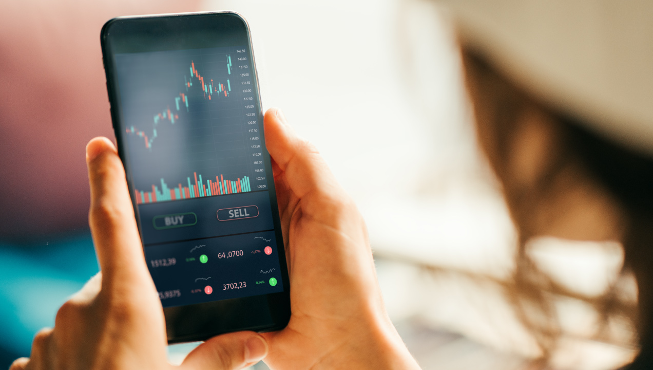 Senhor a mexer no telemóvel e a ver um gráfico de investimento