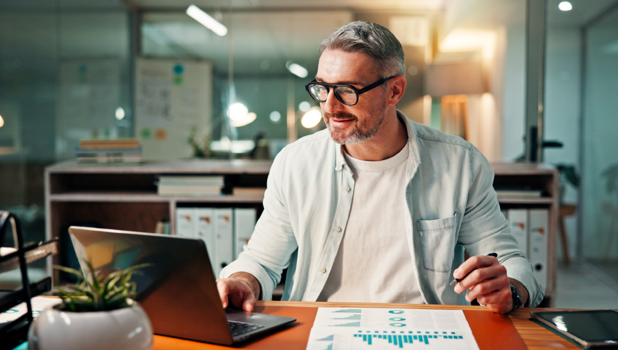 Senhor num gabinete de escritório sentado à secretária a mexer no computador