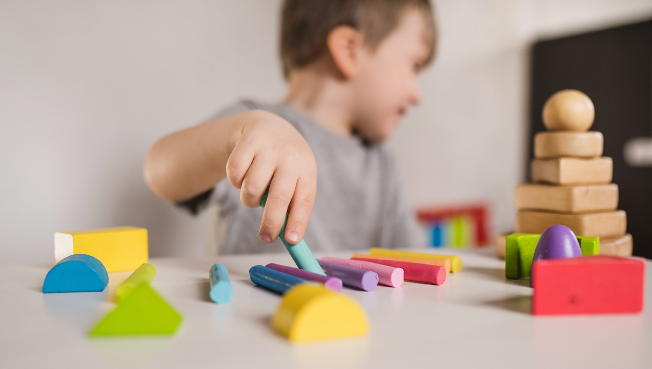 Menino sentado a brincar com vários brinquedos