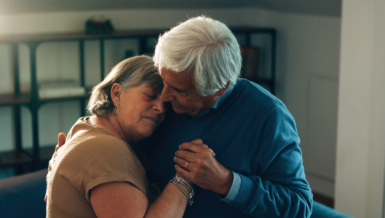 Casal de idosos sentados no sofá abraçados 