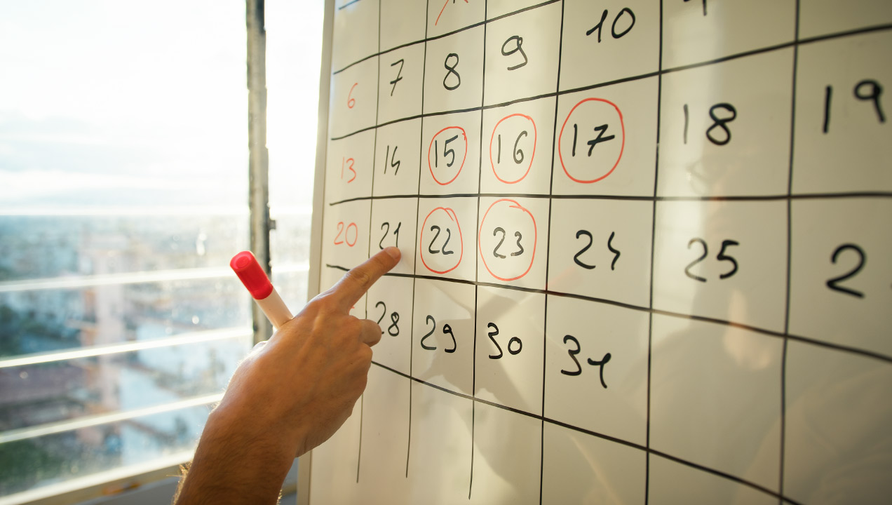 Senhor a preencher dias de férias num calendário desenhado num quadro branco