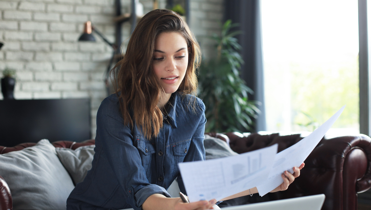 Senhora jovem sentada no sofá e a analisar documentos 