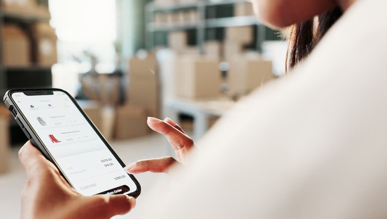 Senhora sentada rodeada de caixas de mudanças e a fazer compras online