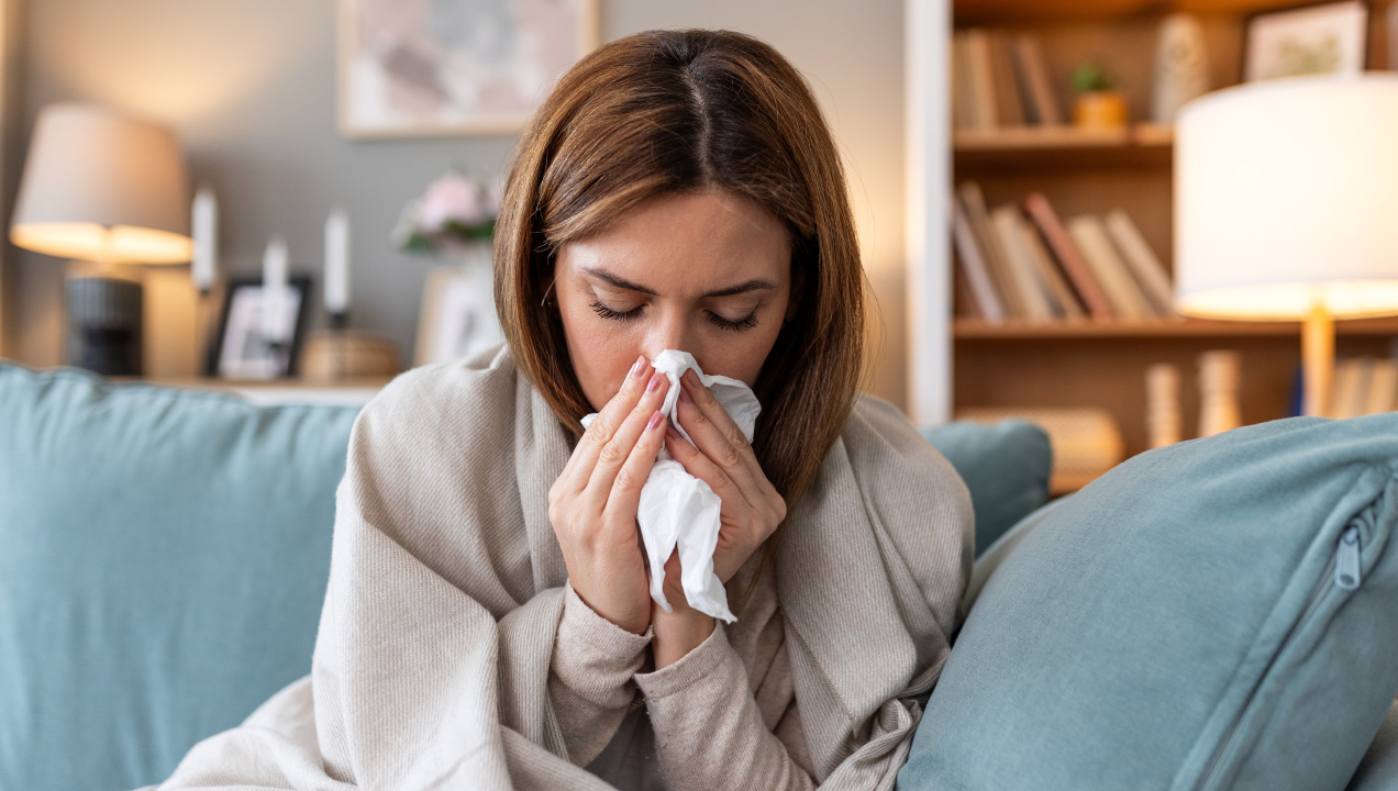 Senhora sentada no sofá a assoar-se