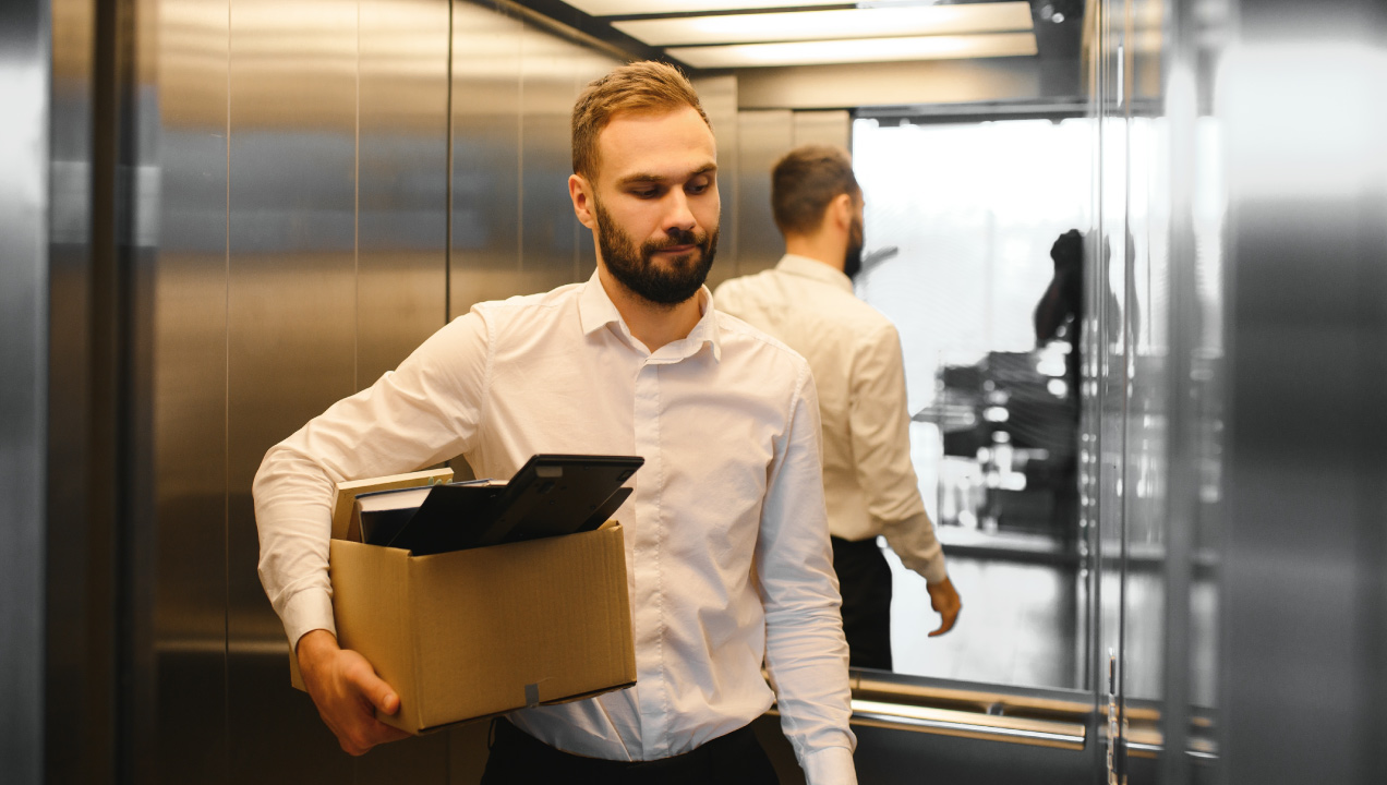 Senhor no elevador a segurar uma caixa com os seus pertences