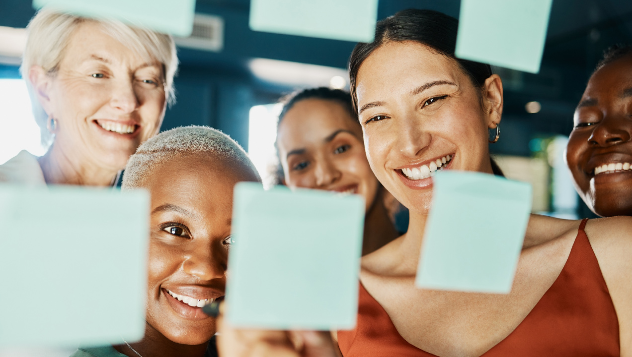 Colegas de trabalho reunidos no escritório felizes a analisarem post its com ideias