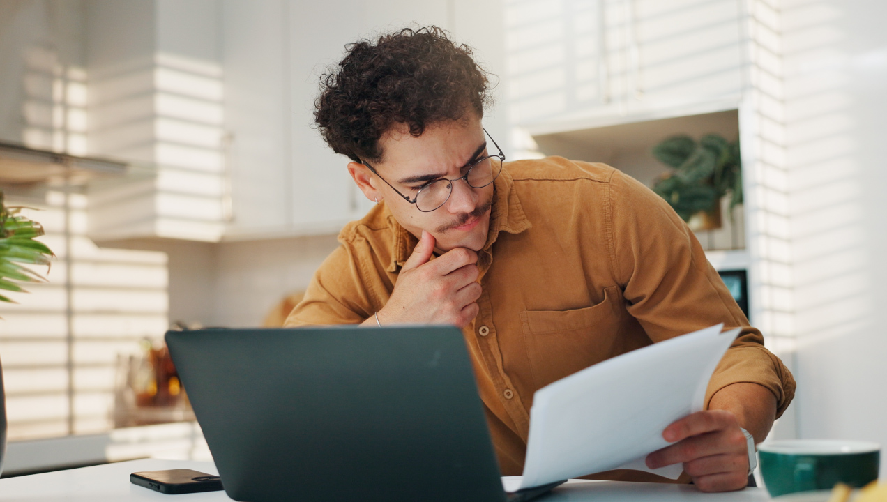 Senhor sentado com o compuador e a analisar documentos