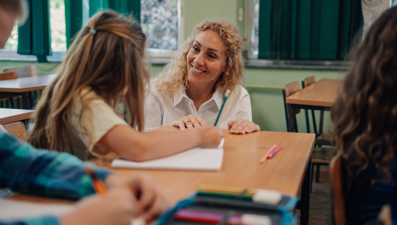 Professora a falar com aluna em ambiente de sala de aula