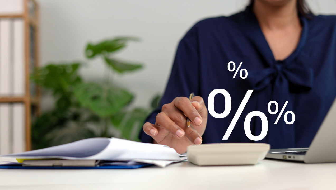 Senhora sentada a fazer contas na calculadora enquanto analisa documentos 