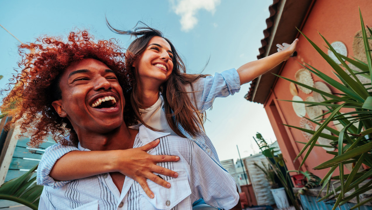 jovem mulher às cavalitas de jovem rapaz, ambos felizes