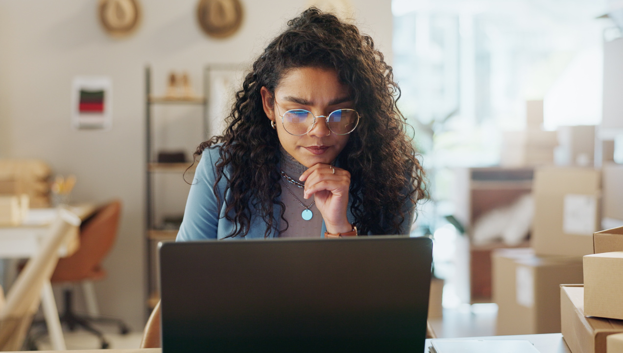 Senhora concentrada e preocupada, sentada a mexer no computador